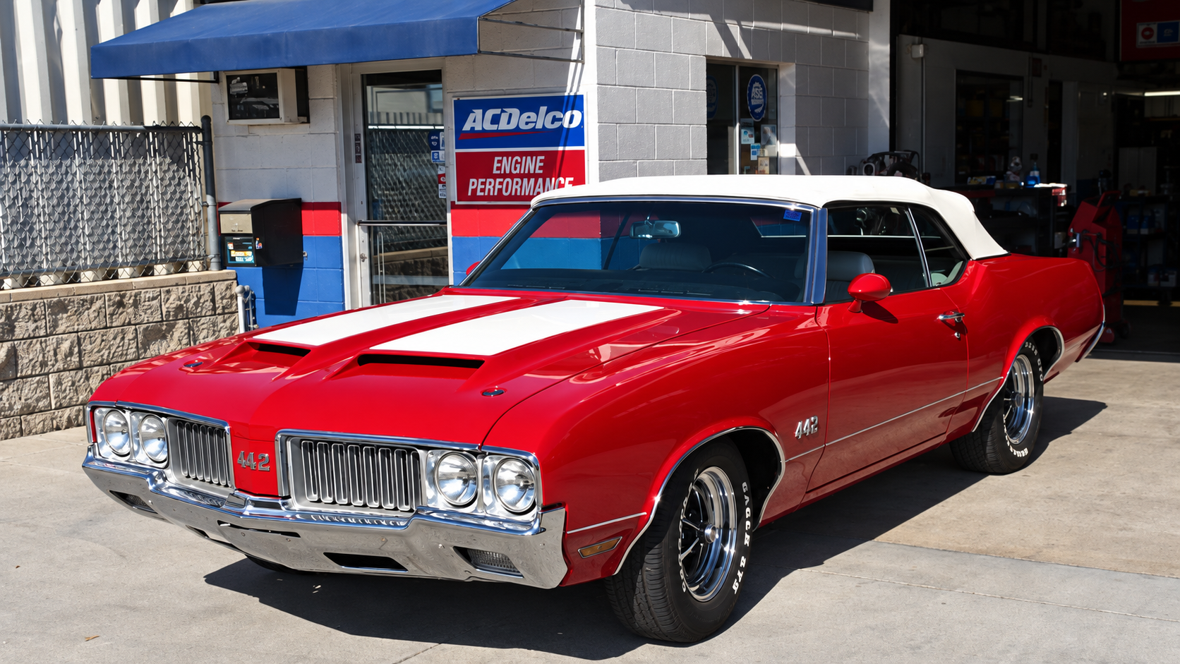 Red Oldsmobile 442 convertible outside the repair shop